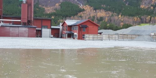 KULER I ELVA: Fabrikkens lagerområde ble oversvømt i oktober 2018 og 25 tonn med skumglasskuler ble ført nedover vassdraget. Foto: Glasopor as.